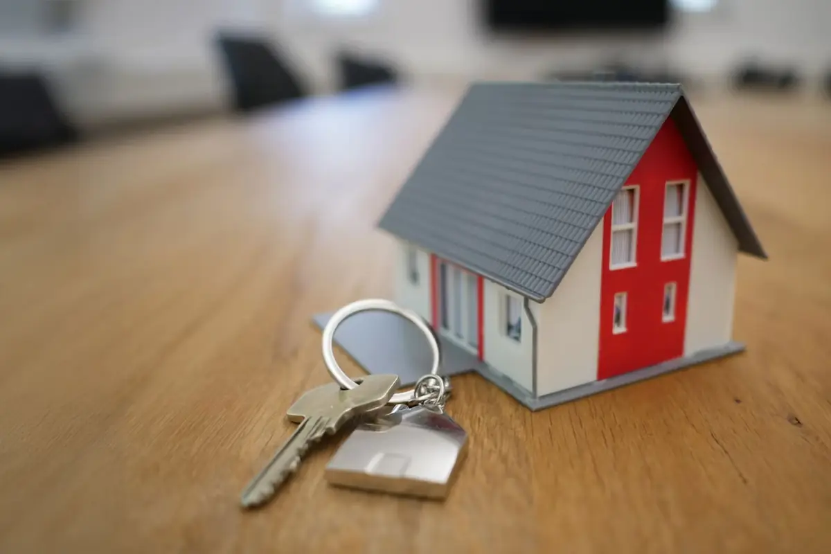 A model house and a set of house keys on a wooden table