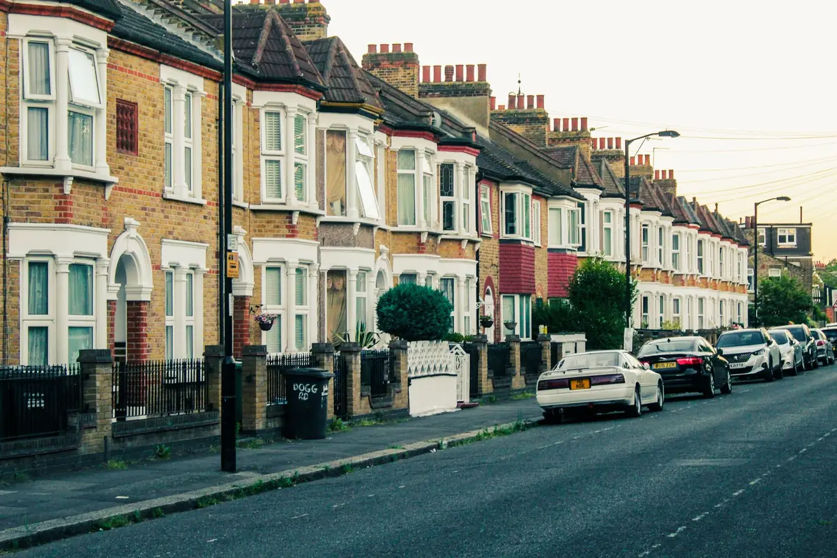 A street of brick terraced houses with bay windows and parked cars